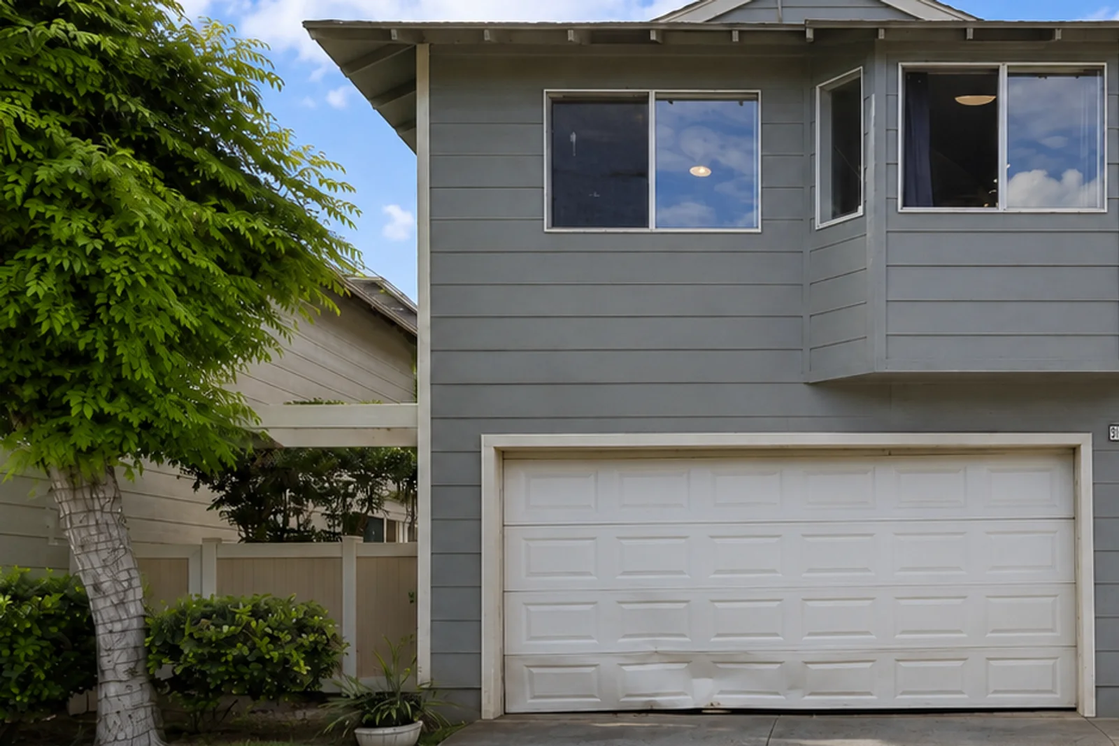 Residential garage door with visible lower-panel impact damage.