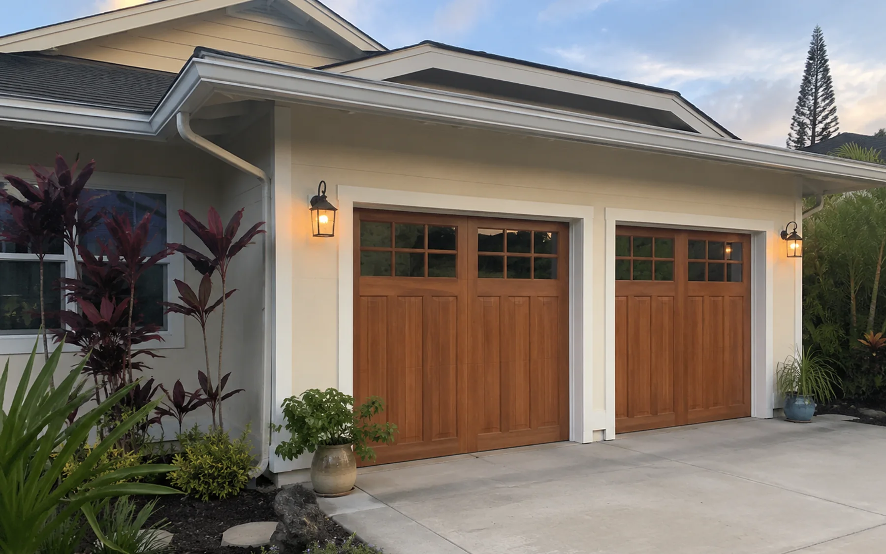 Warm wood-tone garage doors on a clean Oahu home exterior at dusk.