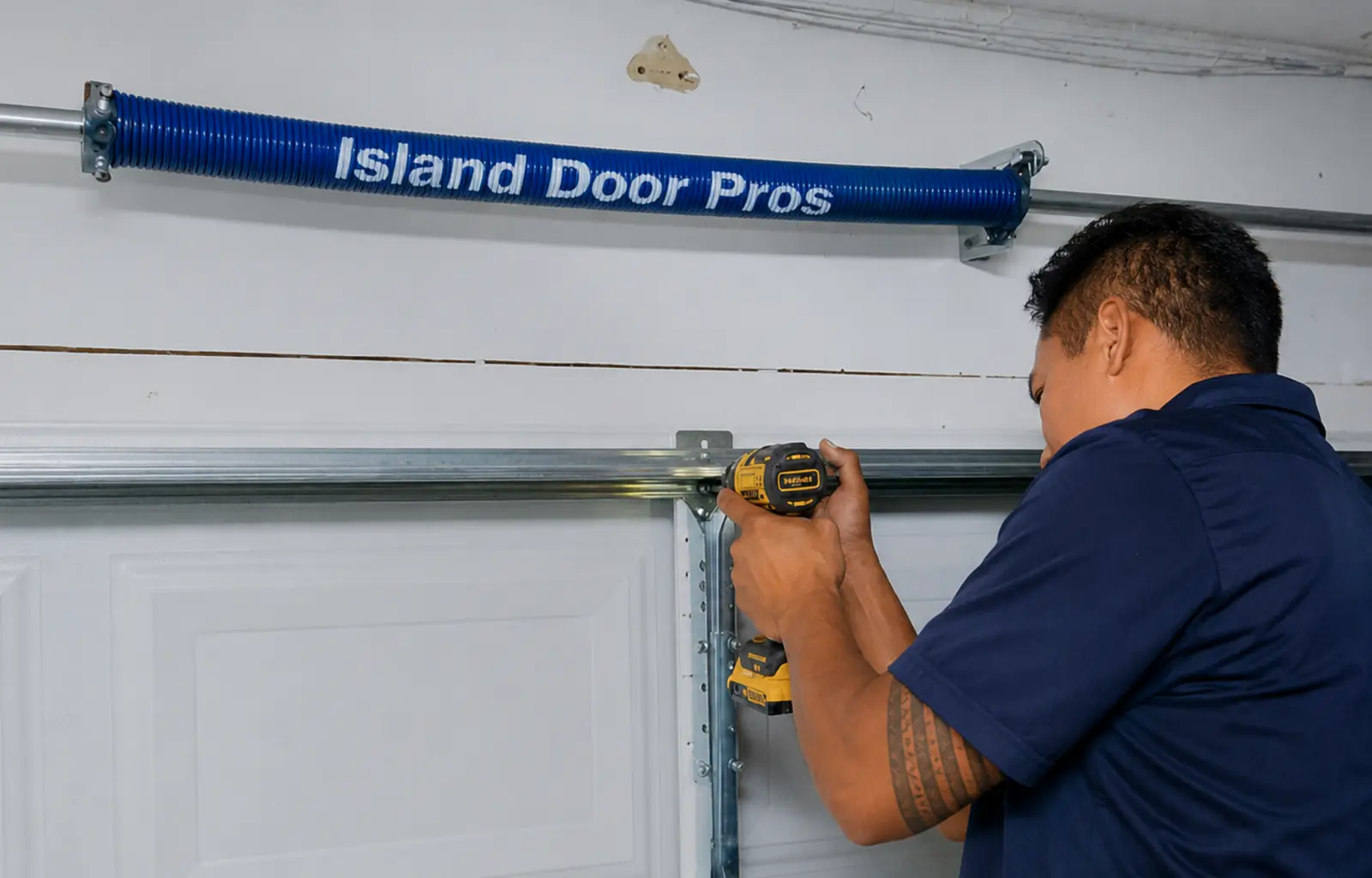Garage door worker installing hardware beneath a blue torsion spring.